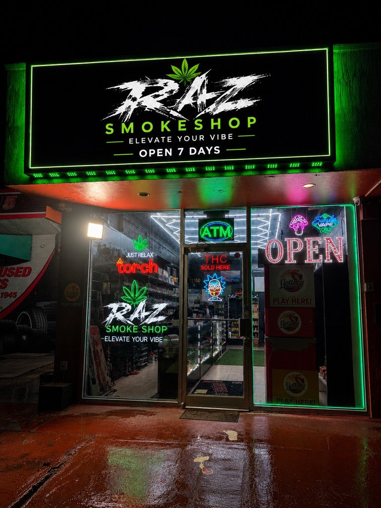 RAZ storefront at night with the illuminated green sign and glass entrance